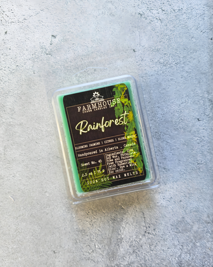 Soy Wax melt packaging labeled 'Rainforest' by Farmhouse Charm Candles on a gray surface.