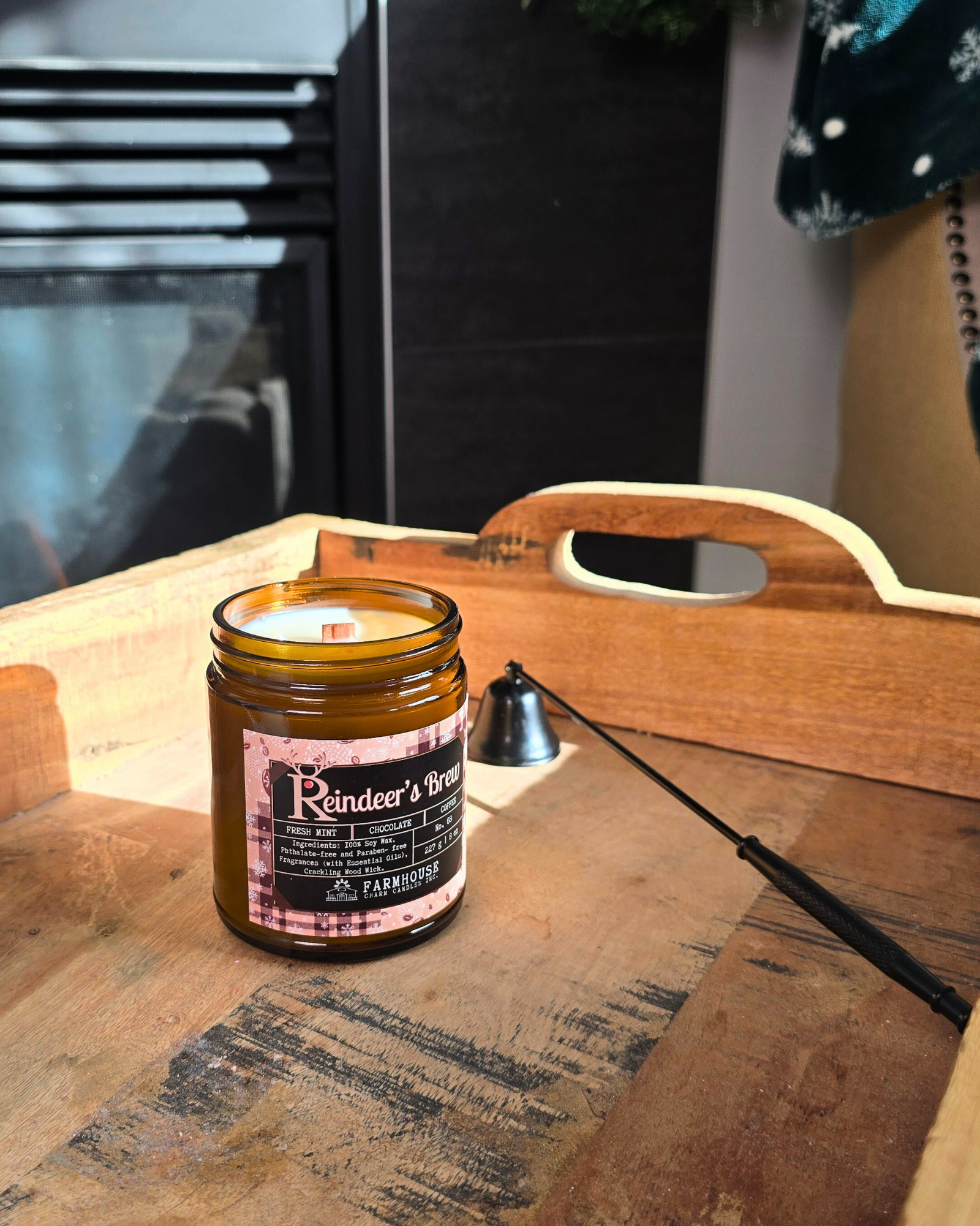 Reindeer’s Brew soy candle in amber jar with warm holiday glow, surrounded by coffee beans, peppermint, and chocolate pieces — cozy Christmas scent from Farmhouse Charm Candles.