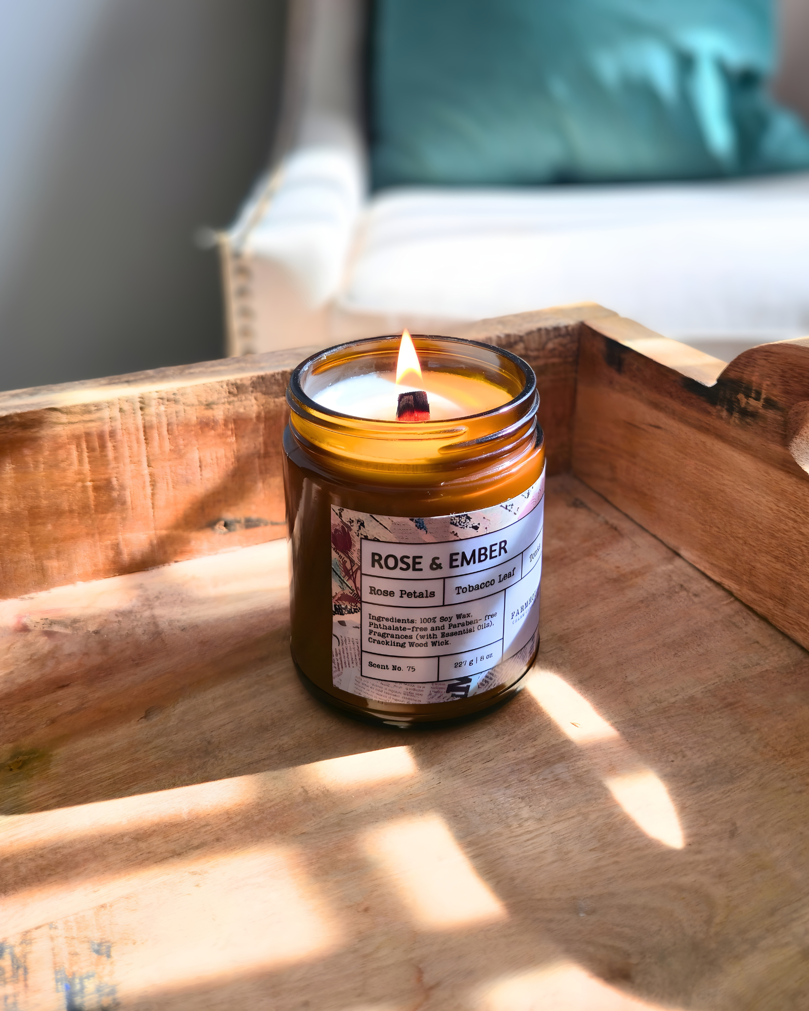 Candle in a glass jar labeled 'Rose & Ember' on a wooden surface with a blurred background by_Farmhouse_Charm_candles