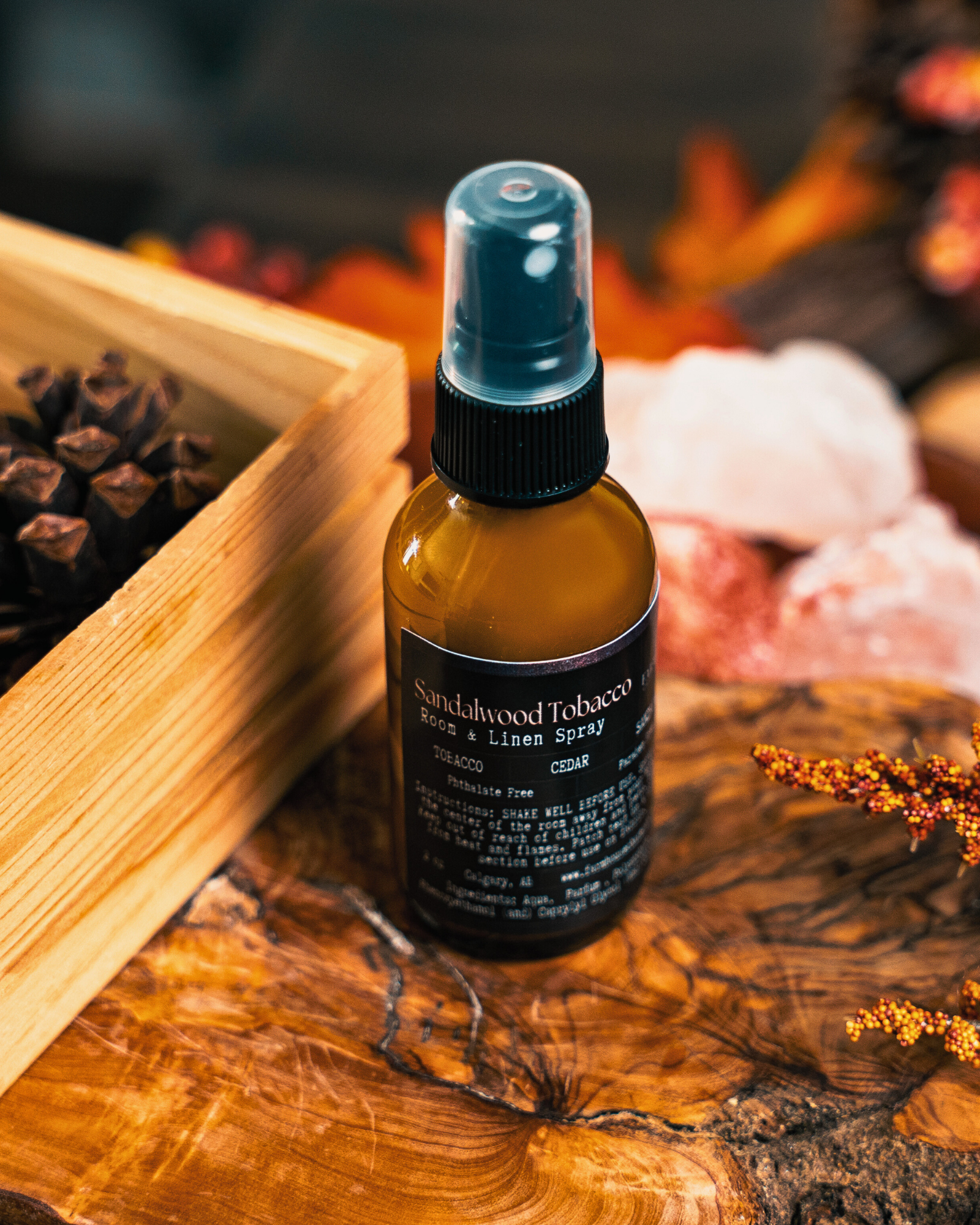 Bottle of Sandalwood Tobacco Room & Linen Spray by Farmhouse Charm Candles on a wooden surface