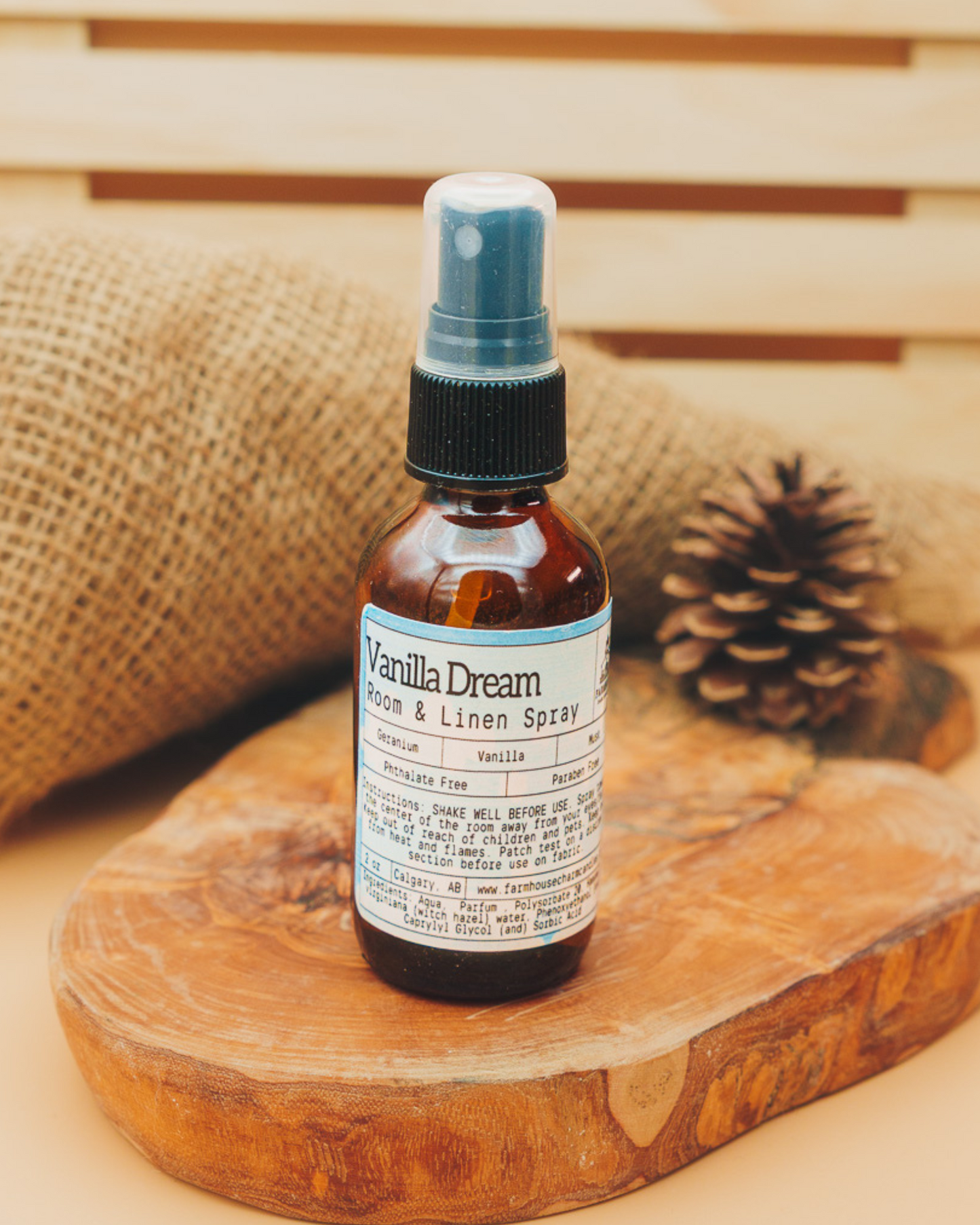 Vanilla Dream room and linen spray by Farmhouse Charm Candles bottle on a wooden surface with a woven background