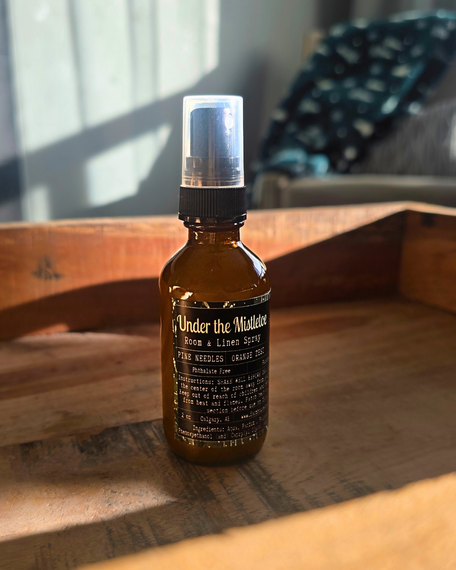 Brown spray bottle with label ' Under the Mistletoe by Farmhouse charm Candles on a wooden surface