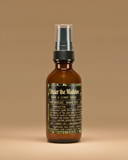 Brown spray bottle with label ' Under the Mistletoe by Farmhouse charm Candles on a beige background