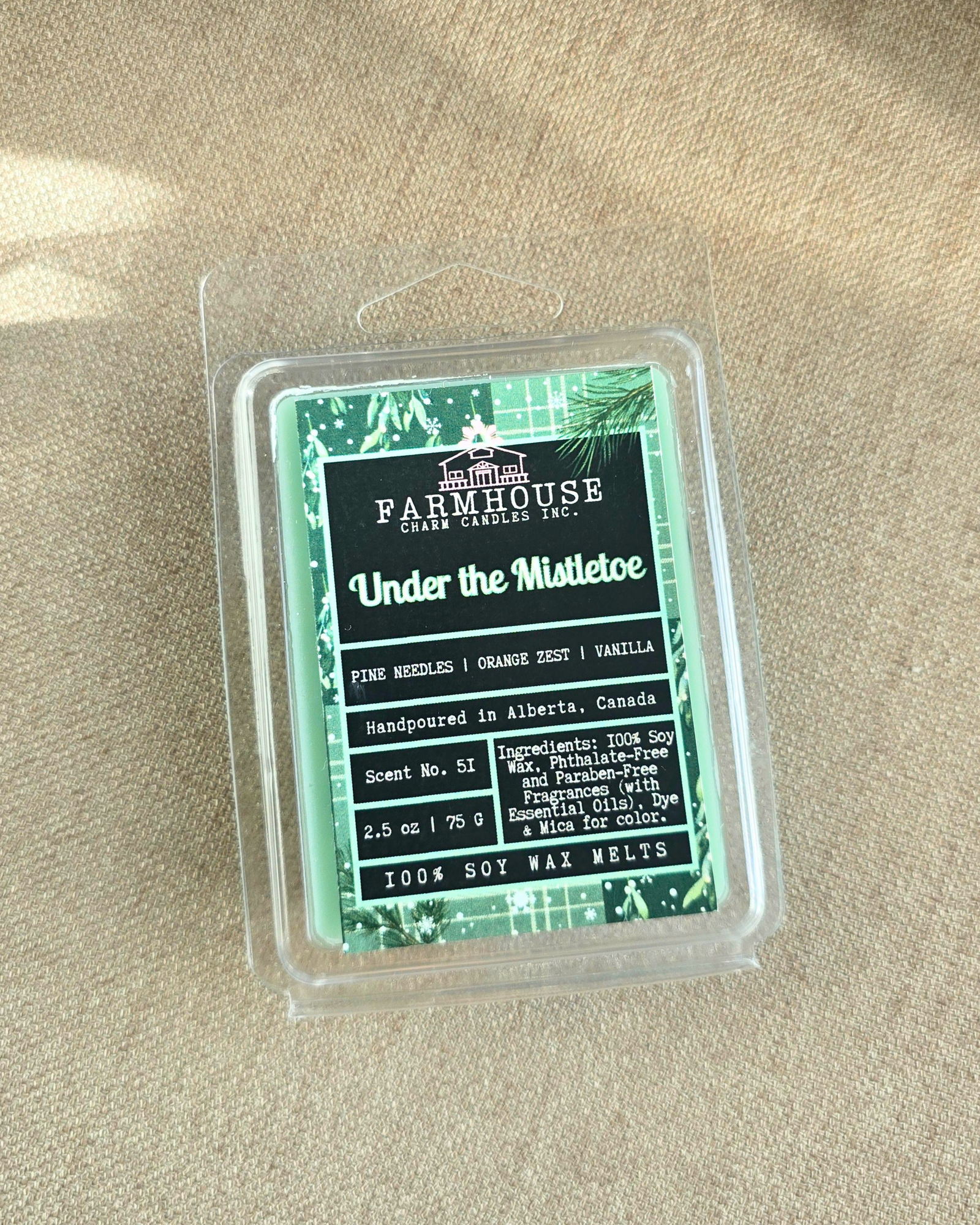 Under the Mistletoe by Farmhouse Charm Candles wax melt package on a beige surface